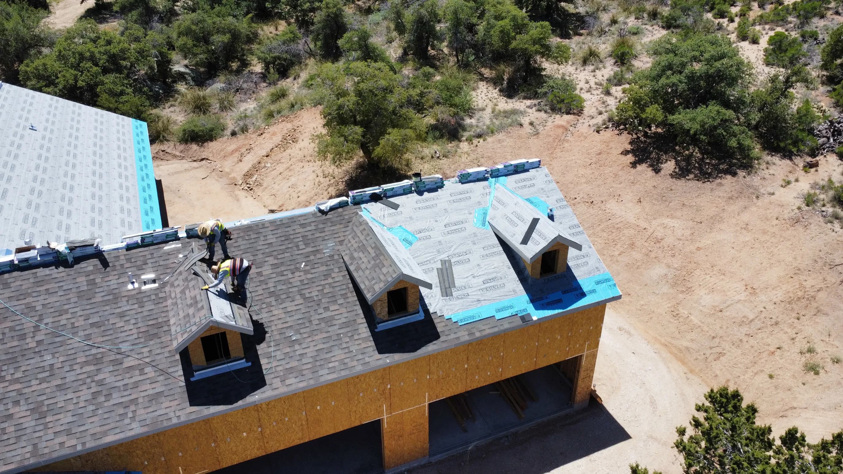 Wide aerial of the finished custom home outside Oracle, AZ — granite boulder field and high-desert scrub oak