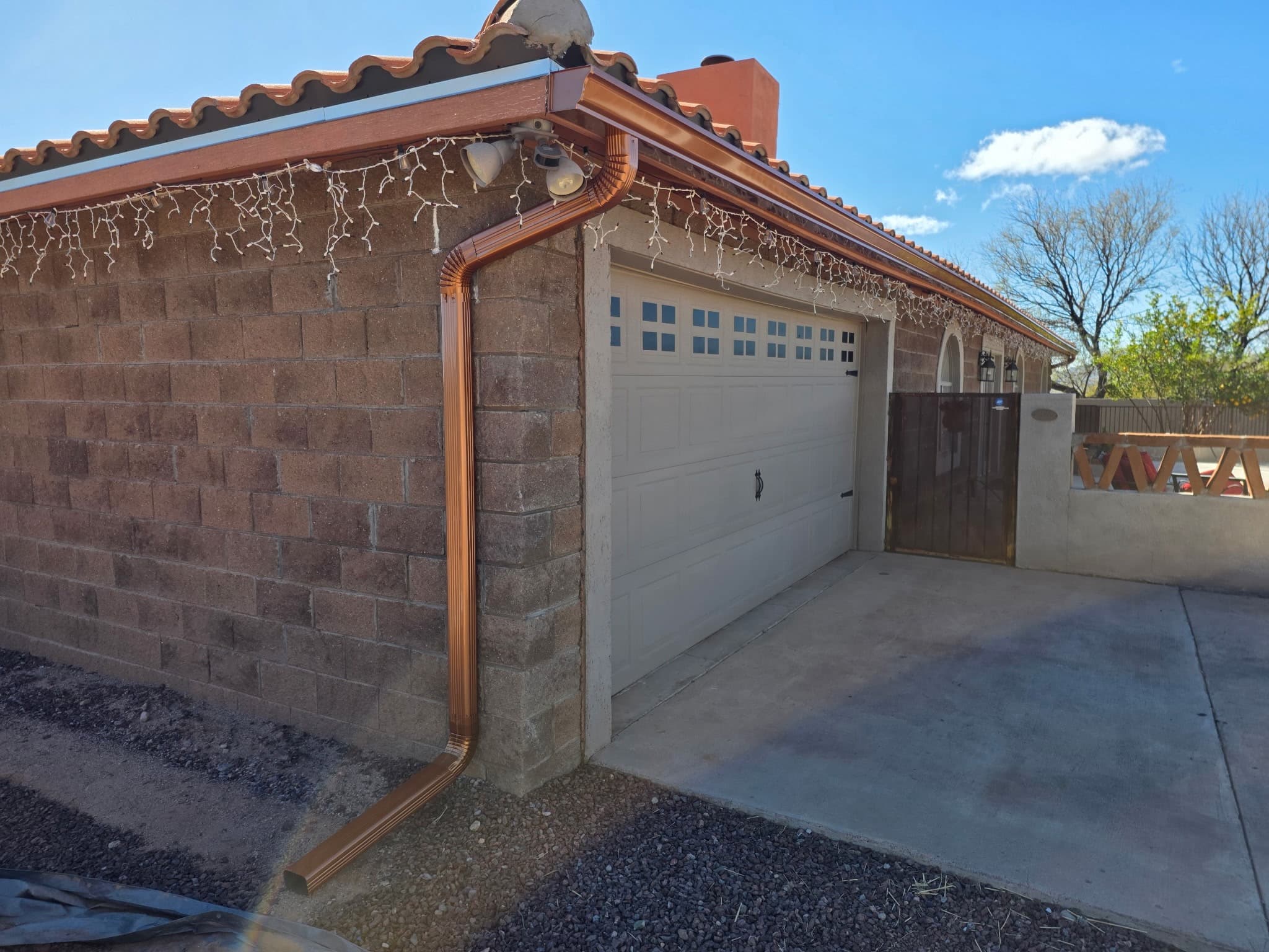 Copper seamless gutter wrapping the corner of a Spanish-tile-roofed Tucson home